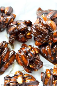 there are many pieces of chocolate covered nuts on the white tablecloth, and one is cut in half to look like an animal's head