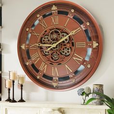 a clock that is on the side of a wall next to candles and vases