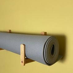 a yoga mat is hanging on the wall next to a wooden rack with a roll