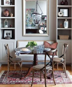 a dining room table with chairs and a couch in front of a bookcase filled with books