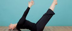 a woman is doing yoga on the floor with her feet in the air and one hand up above her head