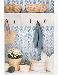 a blue and white tiled wall with baskets on the shelf next to flowers, plants and other items