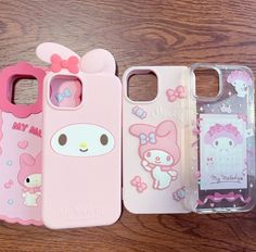 hello kitty phone cases are lined up on a wooden surface, one is pink and the other is white