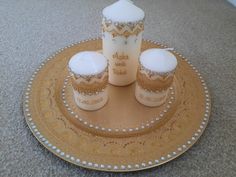 three cupcakes on a gold plate with a candle in the middle and some frosting