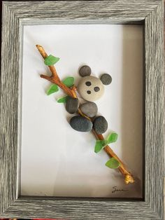 a panda bear sitting on top of a tree branch with rocks in it's mouth