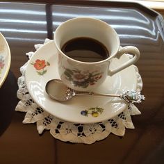 a cup of coffee sitting on top of a saucer next to a plate with spoons