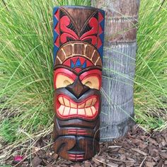 a tiki mask sitting next to a tree