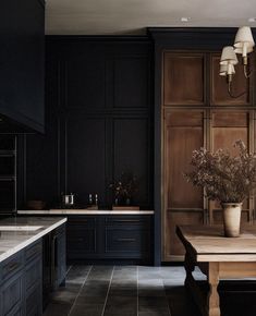 a kitchen with black cabinets and a wooden table in front of the counter top,