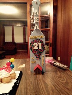 a wooden table topped with cupcakes and a wine bottle shaped like the number twenty