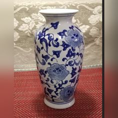 a blue and white vase sitting on top of a red tablecloth covered floor next to a wall