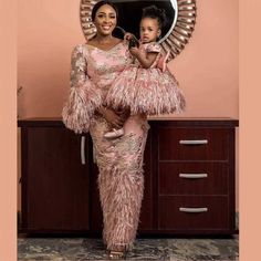 the mother and daughter are posing for a photo in front of a mirror with feathers on it