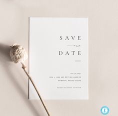 a white save the date card next to a dried flower