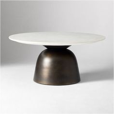 a white table with a black base on a grey background and the top is round