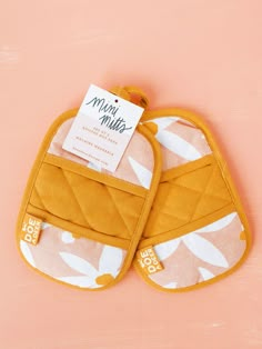 two oven mitts are sitting on a pink surface with a price tag attached to them