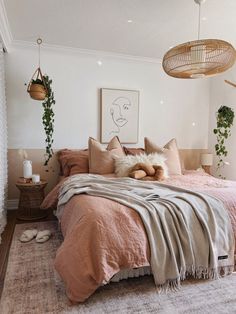 a bed with pillows and blankets on top of it in a bedroom next to plants