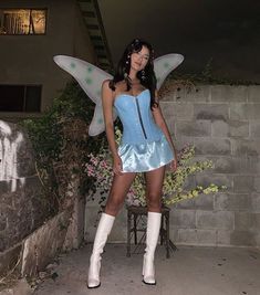 a woman in a blue corset and white boots poses for the camera with her wings outstretched