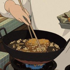 a person cooking food in a pan on top of a stove with chopsticks