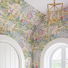 a room with two arched windows and a wallpapered ceiling that has an image of children's toys on it