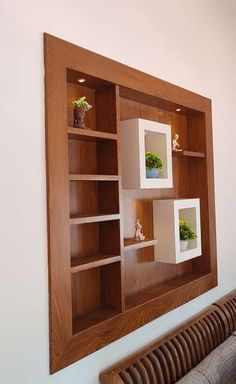 a wooden shelf with plants on it in front of a wall mounted art piece above a couch