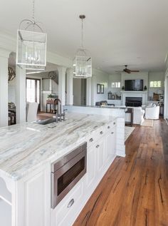 a large kitchen with an island in the middle and wood flooring on the other side