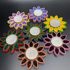 six colorful flower shaped dishes are sitting on a black countertop, with one white plate in the middle