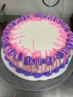 a cake with pink and purple icing on it sitting on top of a table