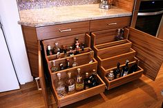 a kitchen with wooden cabinets and drawers filled with bottles