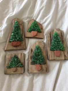 four small wooden trays with plants and rocks in them on a white bed sheet