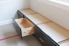 an empty desk with drawers on the bottom and one drawer open in front of it