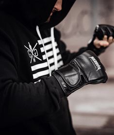 a person wearing a black hoodie and holding a pair of gloves in their hands