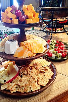 three tiered platters filled with cheese, crackers and fruit on top of a wooden table