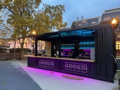 an outdoor bar with purple lighting on the outside