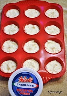 cupcakes in a muffin tin with cream cheese on the top and an empty plastic container