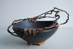 a black bowl sitting on top of a white table next to a wooden spoon and fork