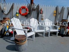 white chairs and life preservers on the deck of a large ship, in front of a fence