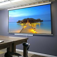 a large flat screen tv mounted to the side of a wall next to a wooden table