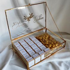 a box filled with lots of gold and white chocolates on top of a table