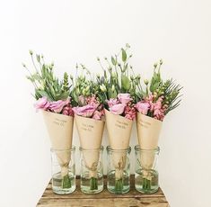 four vases with flowers in them sitting on a wooden table next to each other