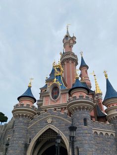 the entrance to an old castle with gold and blue turrets on it's sides