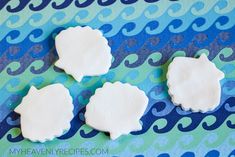 three small white cookies sitting on top of a blue and green table cloth with wavy designs