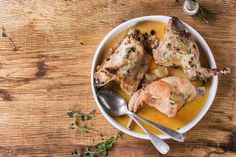 two pieces of chicken in a bowl with potatoes and gravy on the side