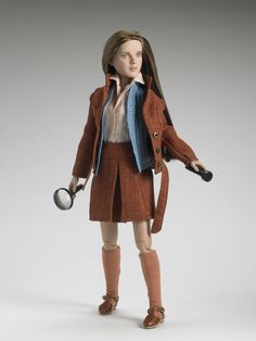 a doll is holding a magnifying glass and wearing a brown coat with blue trim