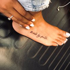 a woman's foot with a tattoo that reads, walk by faith