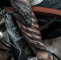 a man's arm with an american flag tattoo on it, sitting in a chair