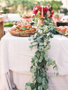 a table topped with lots of food and greenery