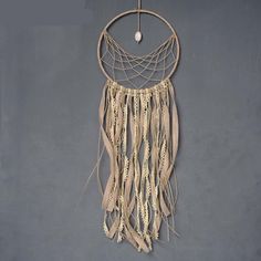 a macrame hanging on the wall with beads and feathers attached to it's sides