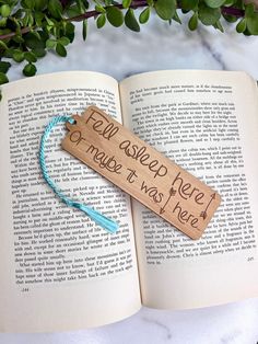 an open book with writing on it sitting next to a plant and some green leaves