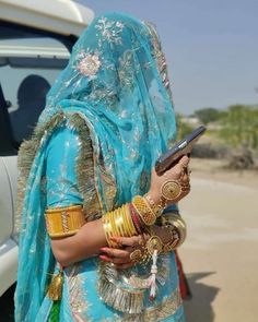 a woman in a blue sari holding a cell phone