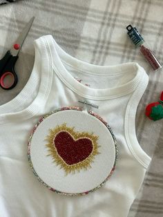 a white shirt with a red heart on it next to scissors and other crafting supplies