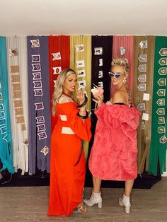 two women standing next to each other in front of colorful backdrop